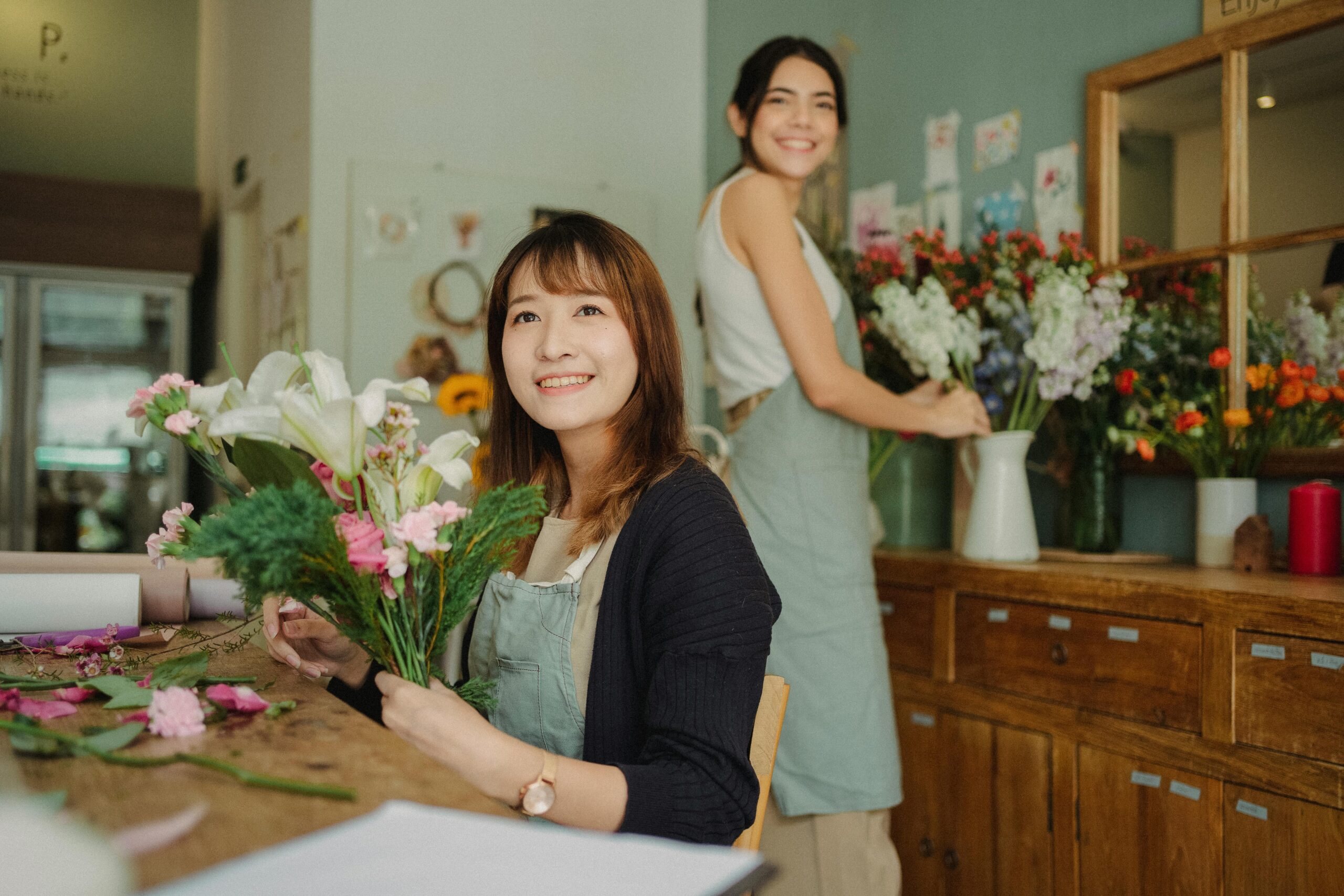 Glücklicher Asiatischer Florist, Der Blumenstrauß Mit Assistent Macht